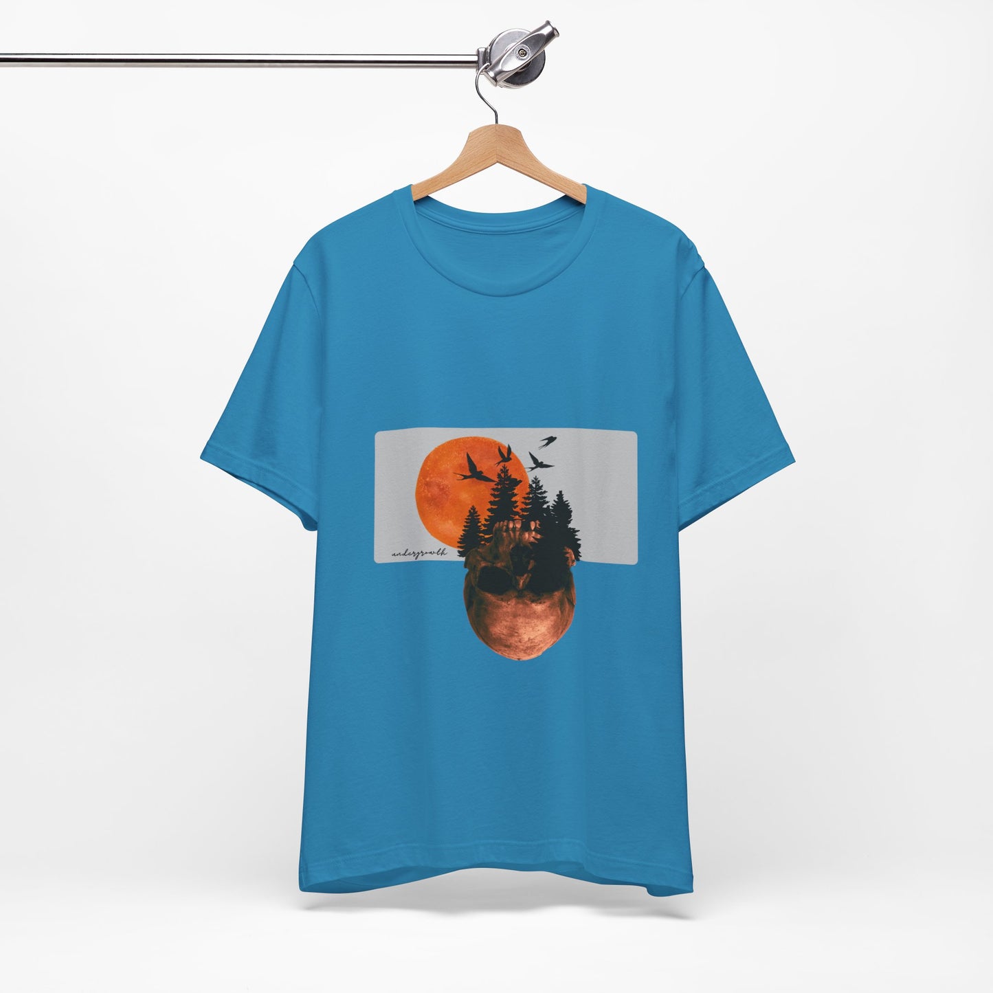 Blue t-shirt with a graphic design of a sunset over trees and birds on a hanger against a white background
