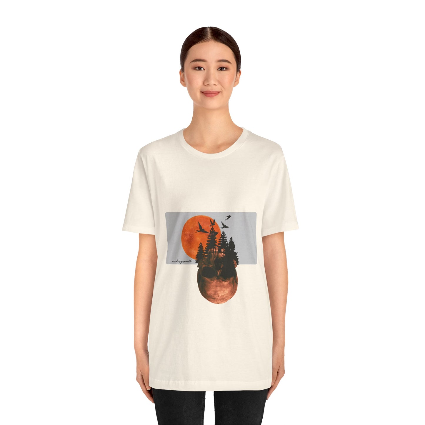 Person wearing a white t-shirt with a graphic design of trees and a moon.