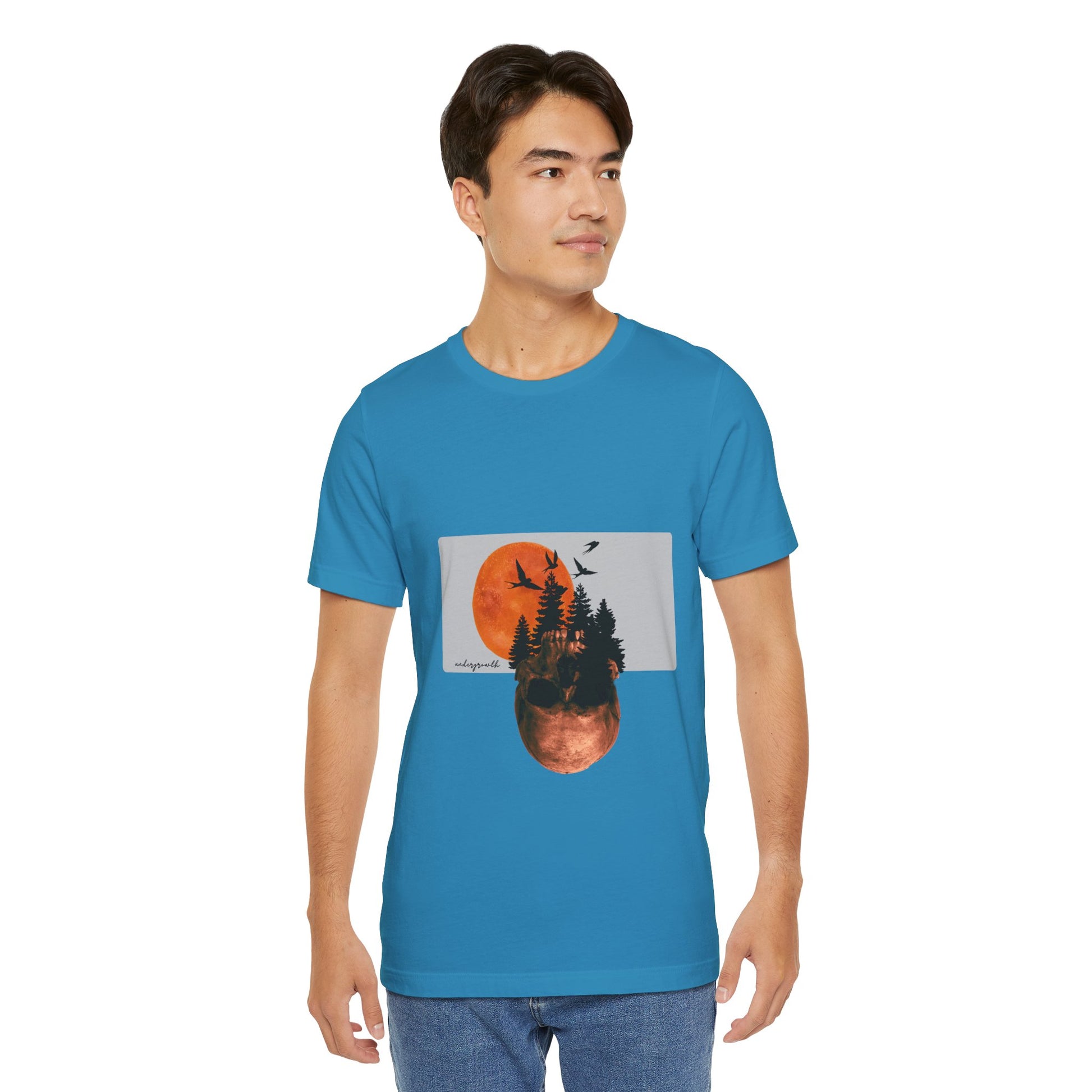 Person wearing a blue t-shirt with a graphic design of trees and birds.