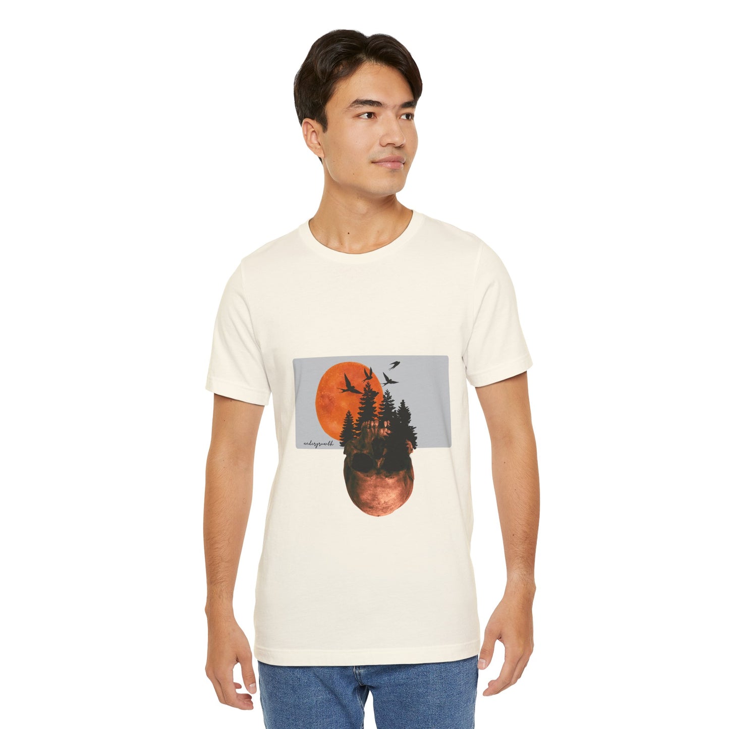 Man wearing a white t-shirt with a graphic design of trees and a sunset.