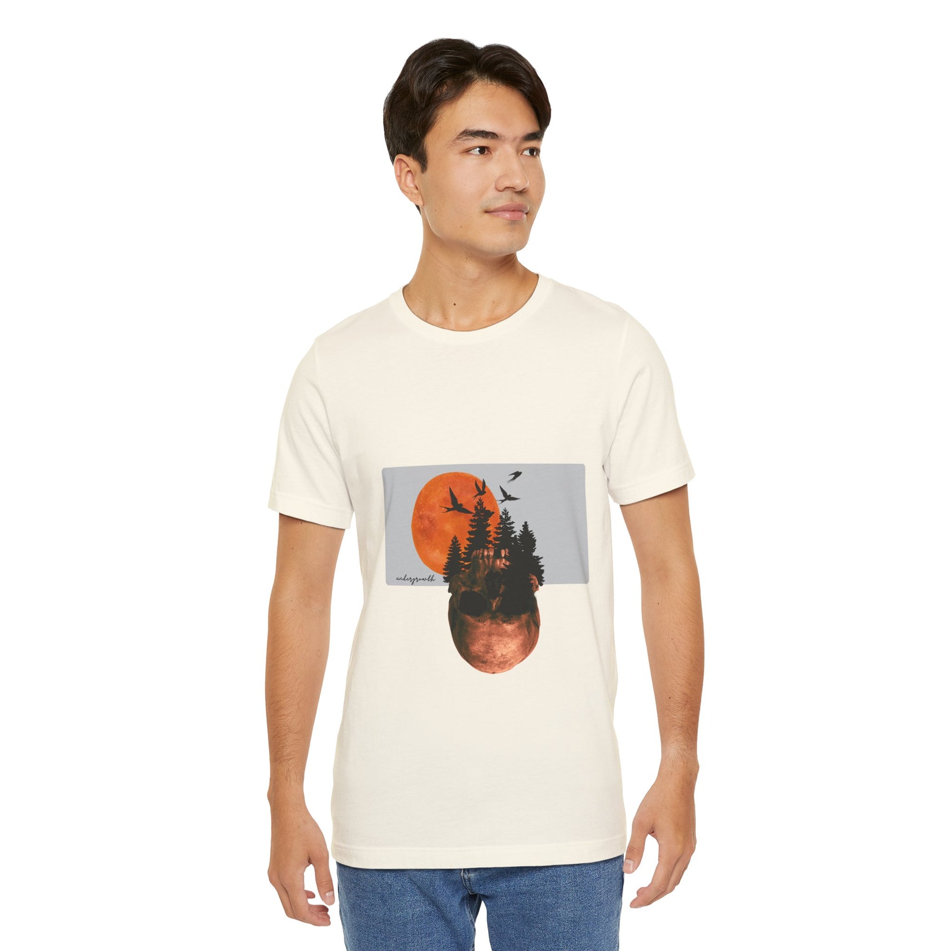 Man wearing a white t-shirt with a graphic design of trees and a sunset.