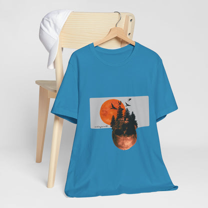 Blue t-shirt with a graphic design of a sunset over trees on a hanger against a white background.